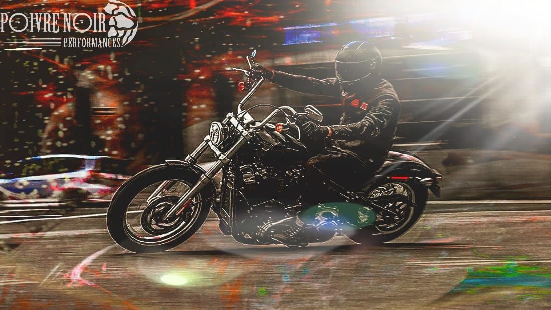 Un motocycliste circulant la nuit, sous les lumières de la ville.