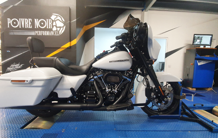 Moto Harley-Davidson blanche sur un banc d'essai, dans un garage.