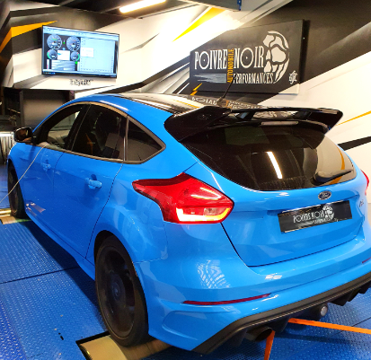 Ford Focus RS bleue sur un banc d'essai, roues noires, aileron noir, à l'intérieur d'un magasin.