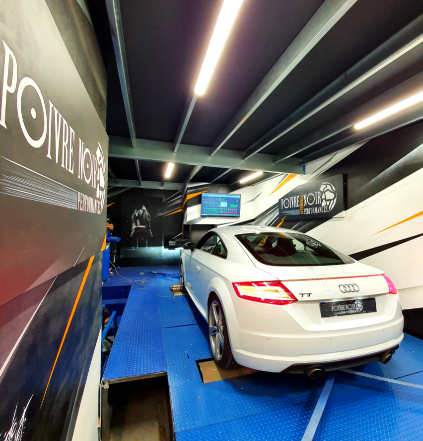 Audi TT blanche sur un dynamomètre dans un garage, testée pour ses performances.