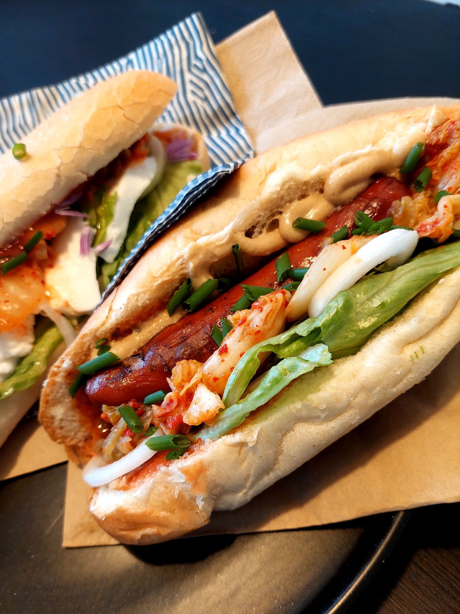 Deux hot-dogs gastronomiques sur du papier brun.