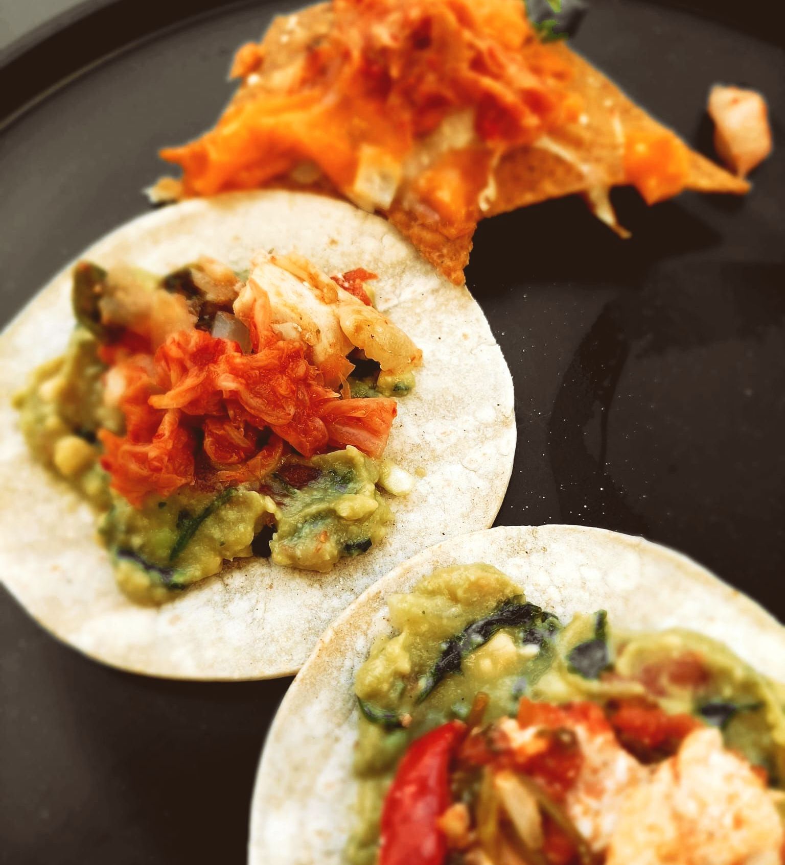 Un gros plan de deux tacos sur une assiette noire