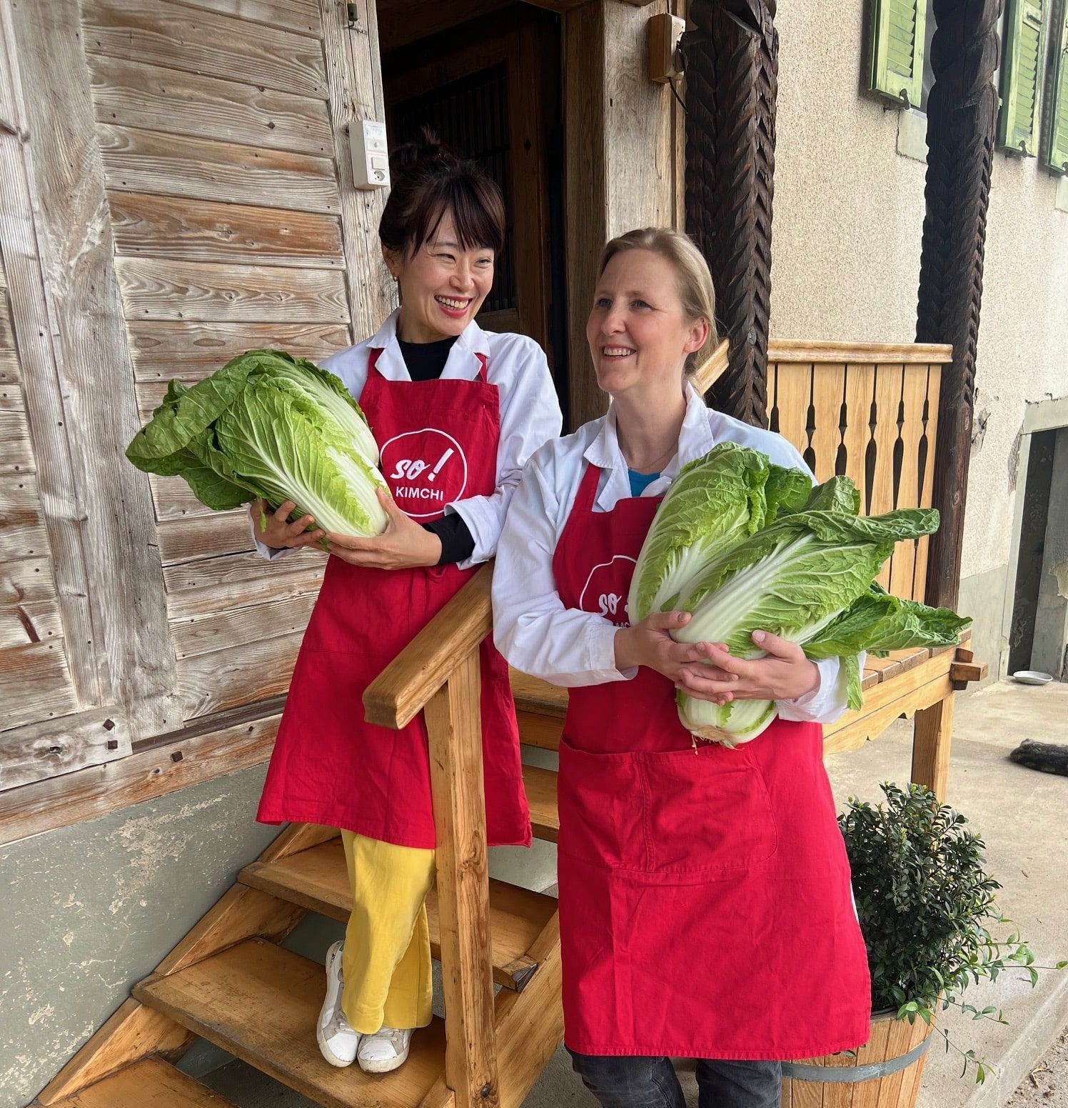 Dorit et Soyoung portant des tabliers rouges se tiennent côte à côte dans une cuisine.