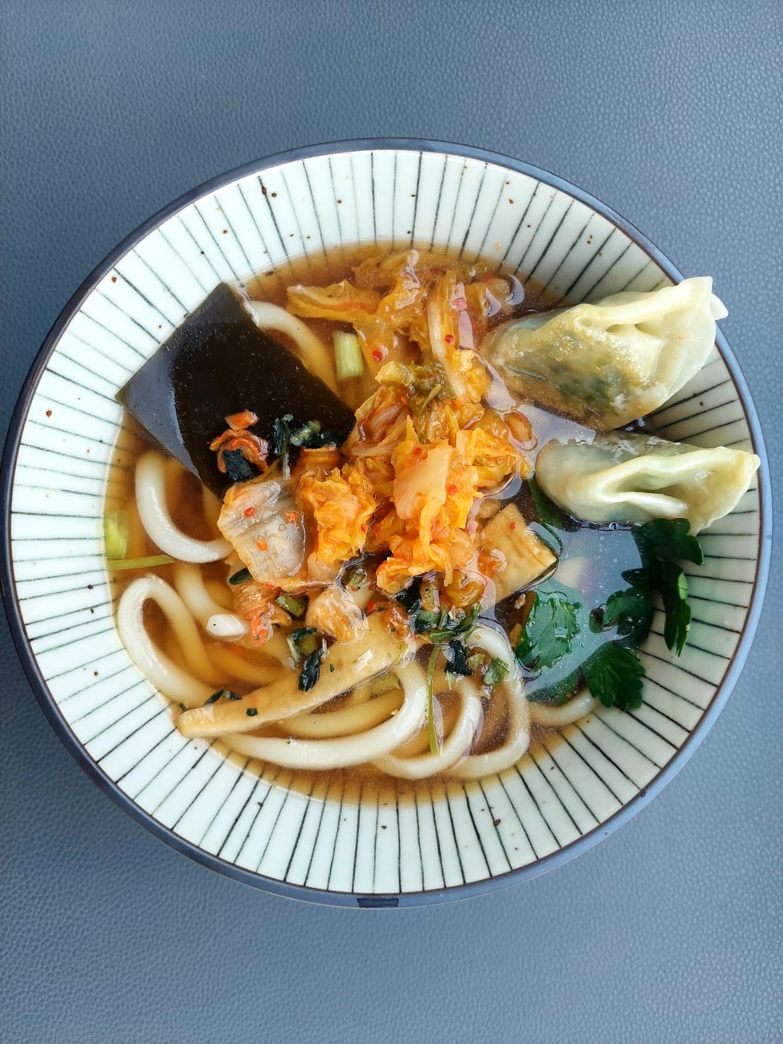 Un bol de nouilles et de boulettes dans une sauce sur une table.