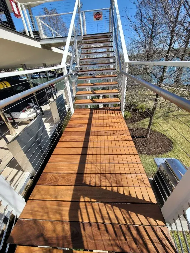 Wooden staircase with metal railings, leading up to an elevated platform, outdoor setting.
