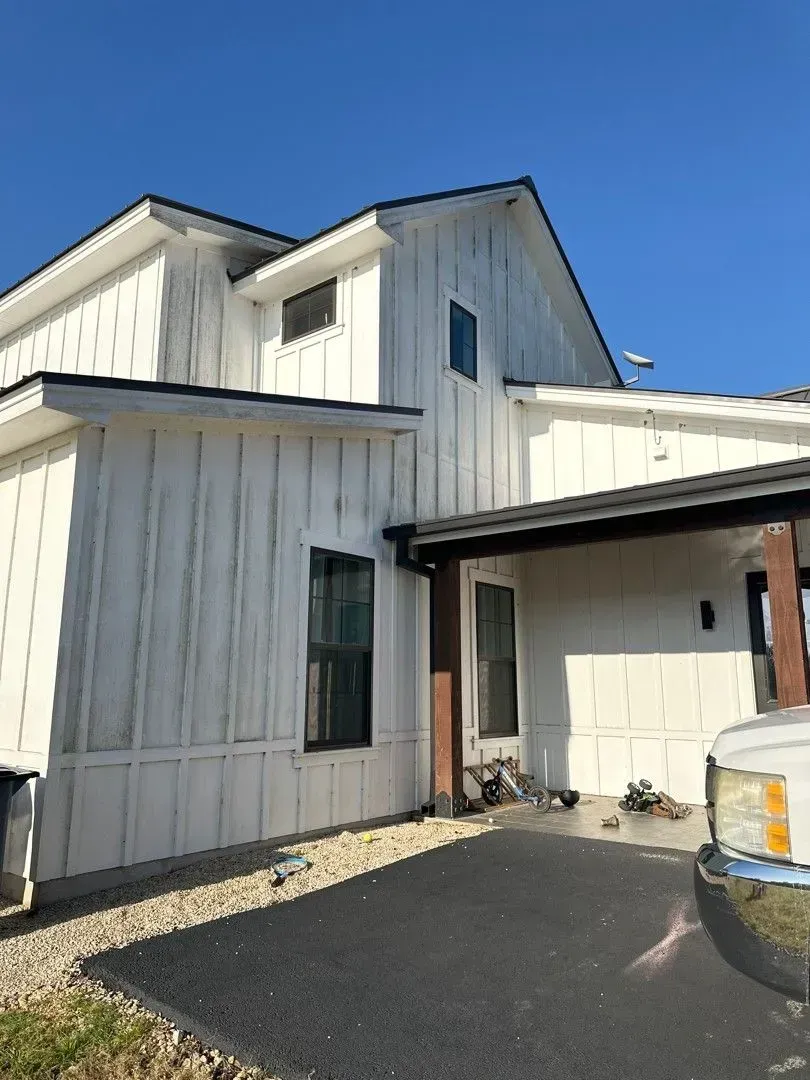 White board and batten sided house with black roof and windows.
