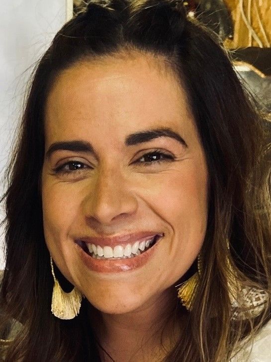 a close up of a woman 's face smiling and wearing earrings .