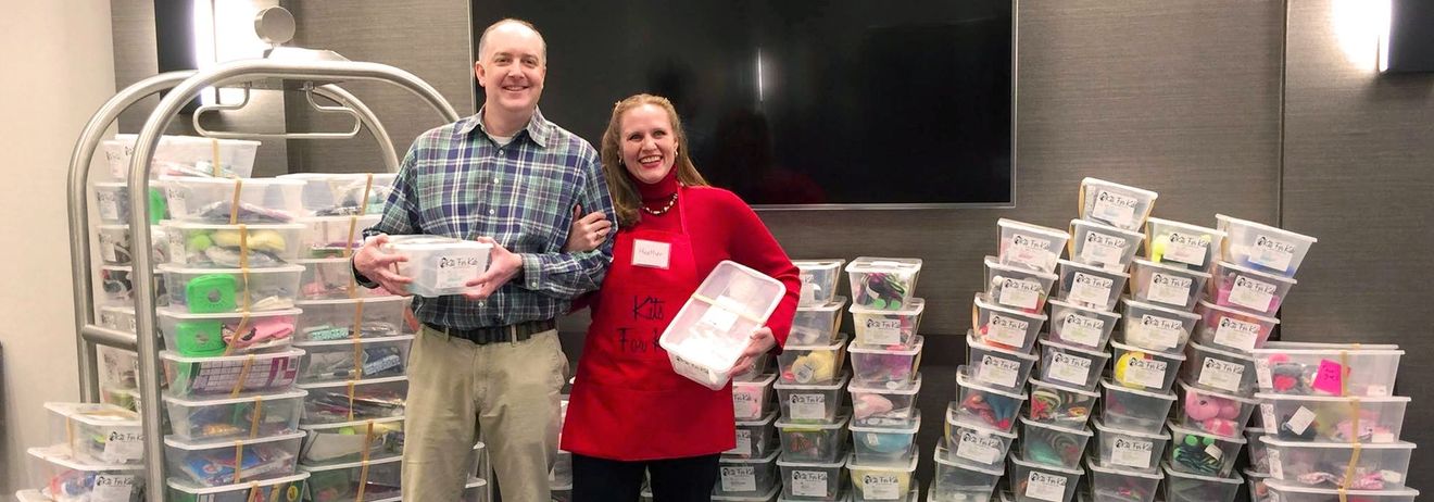 A man and a woman are standing in front of a pile of plastic bins.