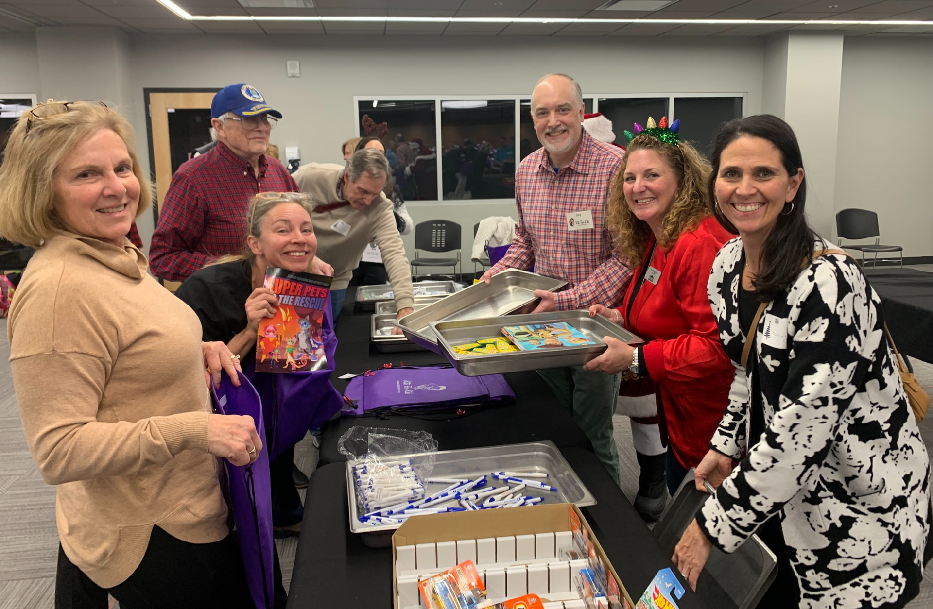 A group of people are standing around a table holding trays of food.