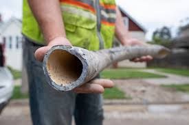 A man is holding a large lead pipe in his hands.