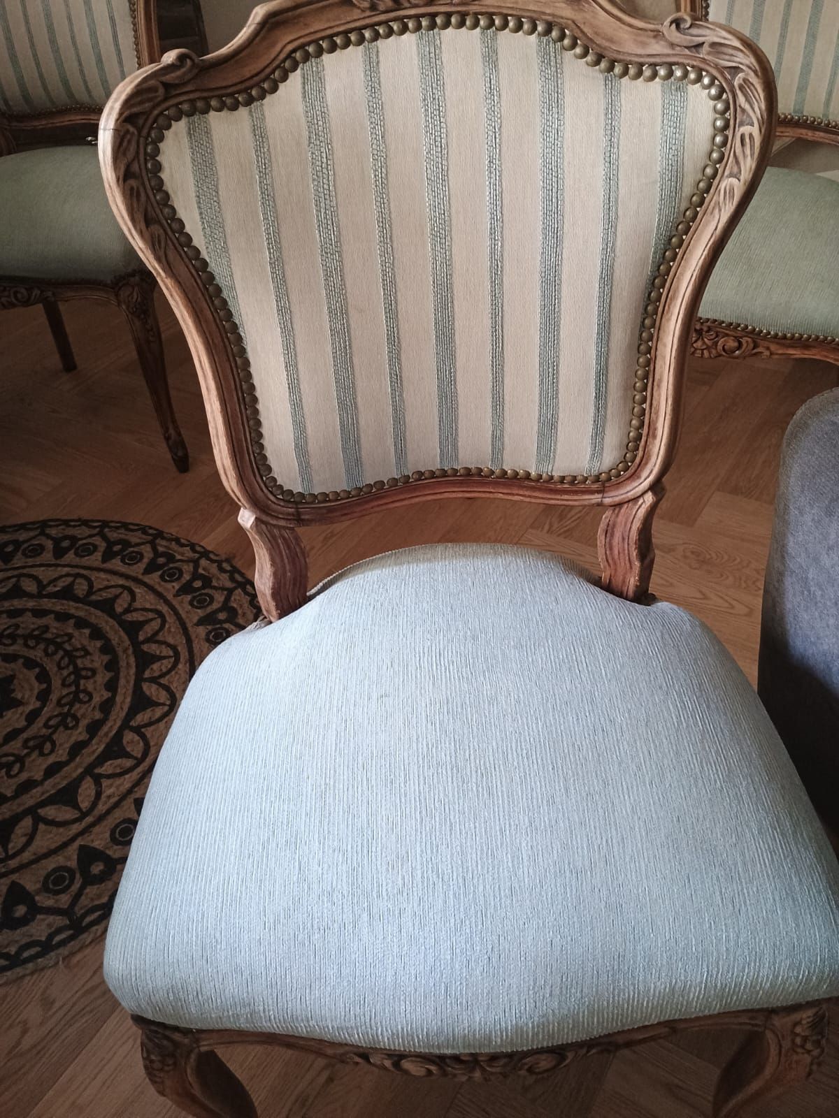 Una silla de estilo vintage con estructura de madera tallada, respaldo de rayas claras 