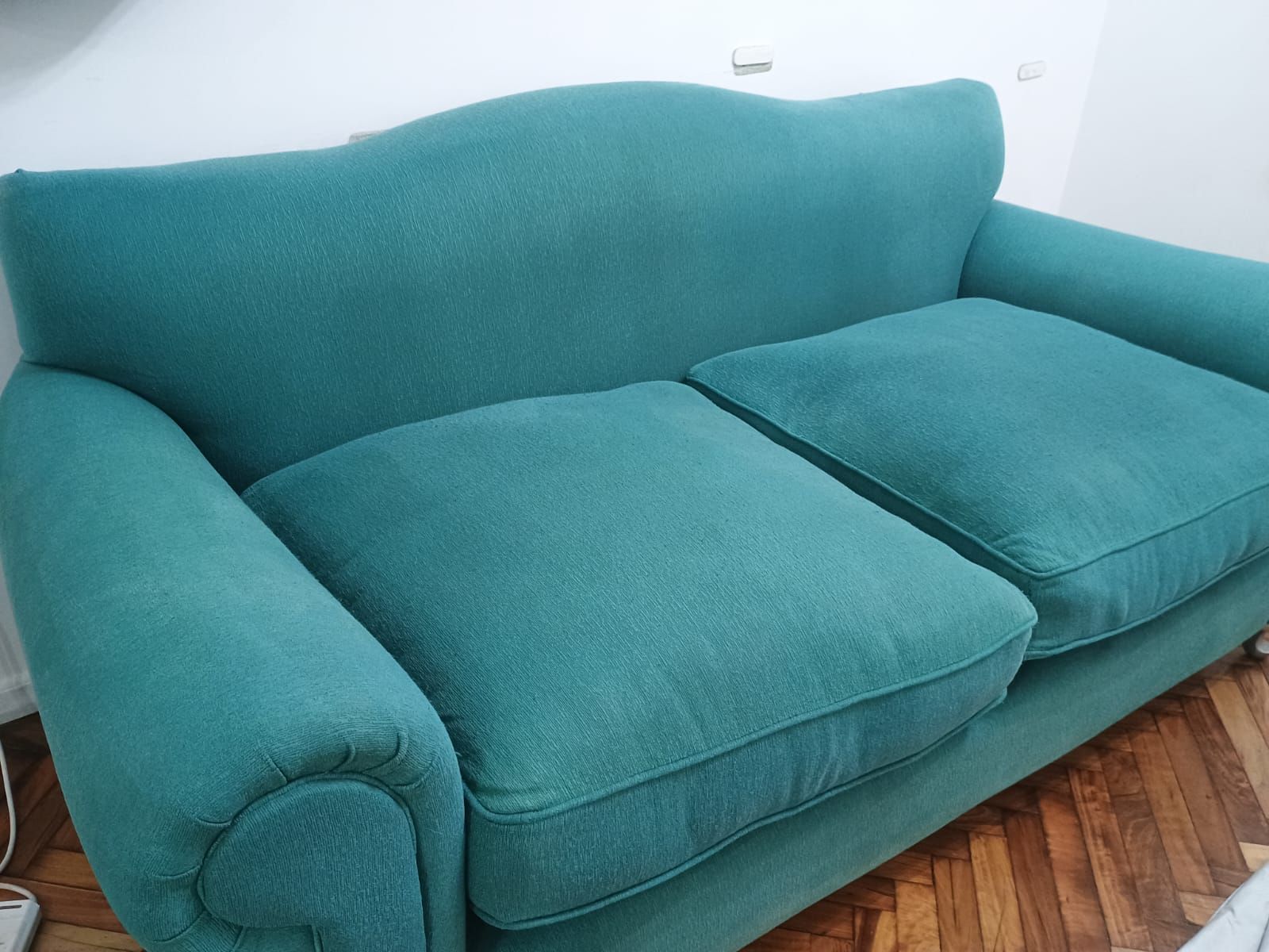 Un colchón blanco con un estampado de volutas grises, colocado frente a un cabecero marrón oscuro en un dormitorio.