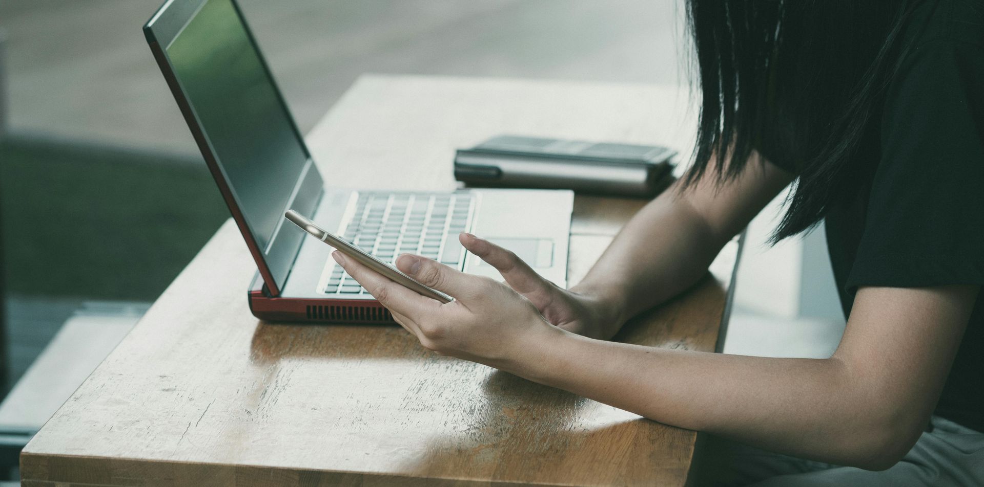 Person using a laptop, holding a pen. They are sitting at a table.