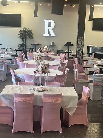 A large room filled with tables and chairs and a large letter r on the wall.