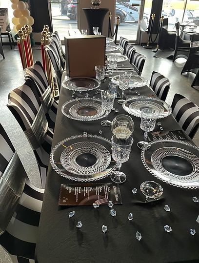 A long table with plates , glasses , and candles on it.