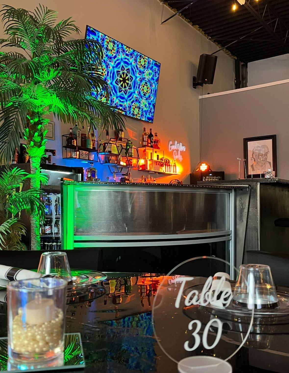 Interior bar with palm tree, illuminated bar, and a table number 30.
