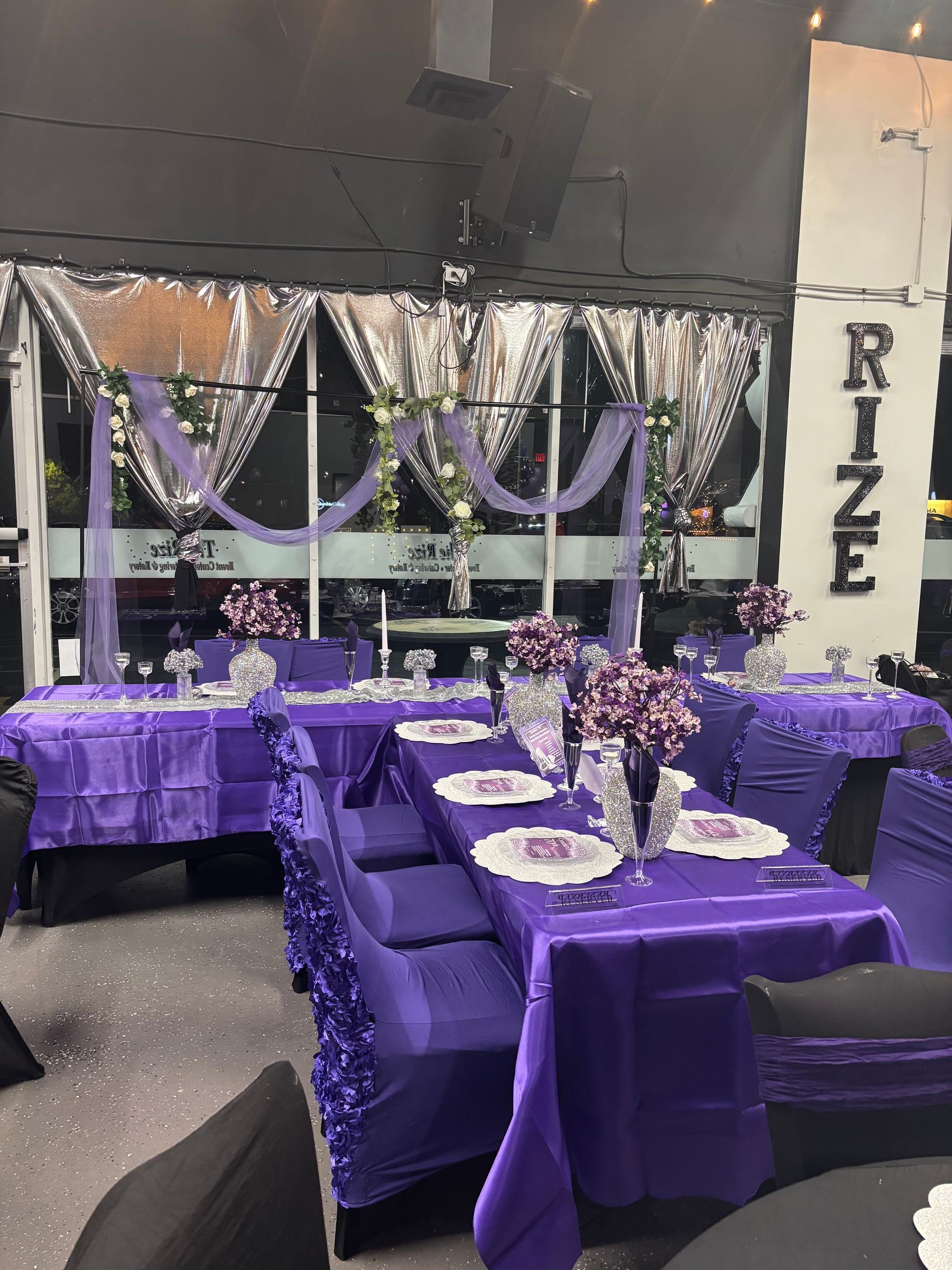 Purple decorated tables and chairs in a venue with window decor, including 
