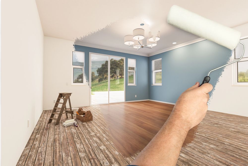 Dipingere a mano una stanza luminosa e vuota con una parete d'accento blu e pavimento in legno.