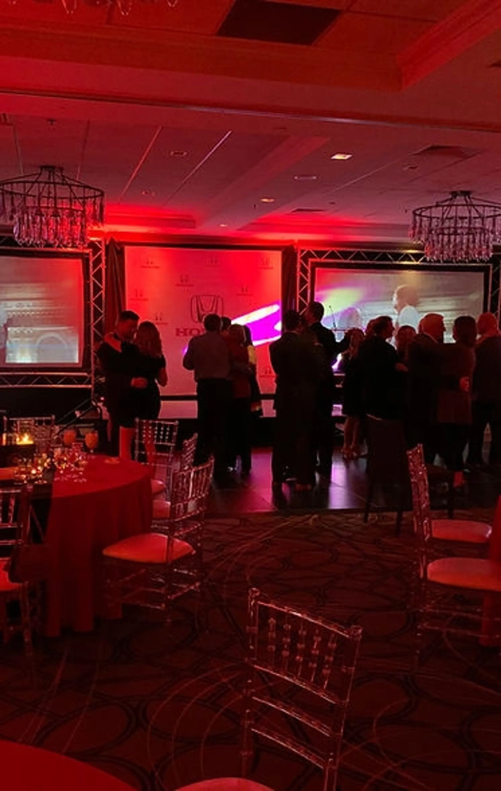 A group of people are dancing in a room with red lights.