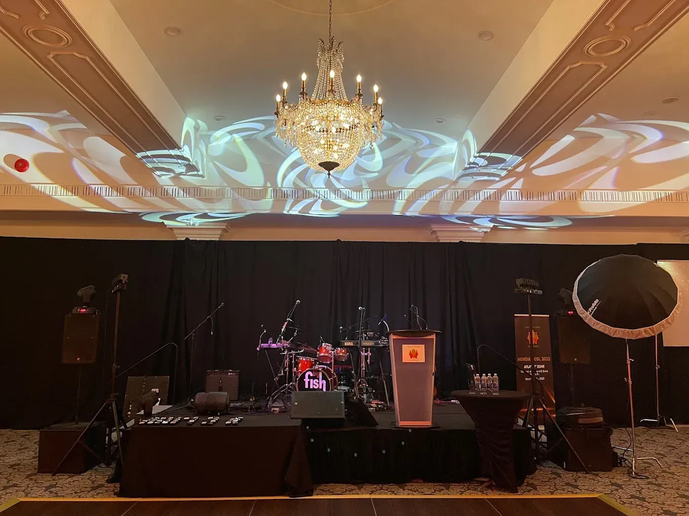 A large room with a stage and a chandelier hanging from the ceiling.