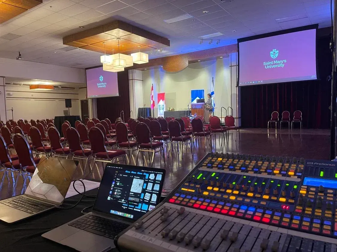 A conference room with a laptop and a mixer in front of it.