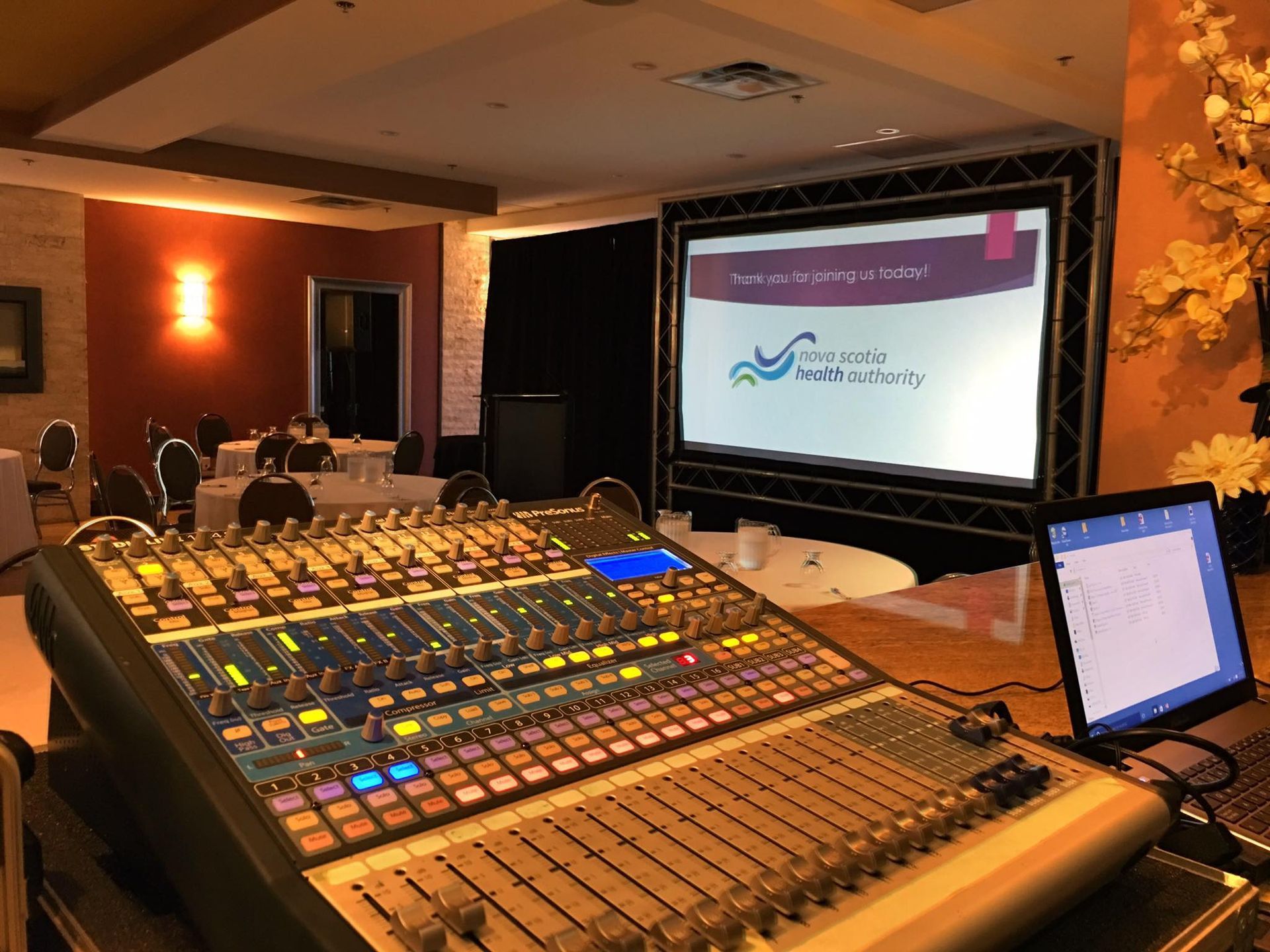 A mixer is sitting in front of a large screen in a room.