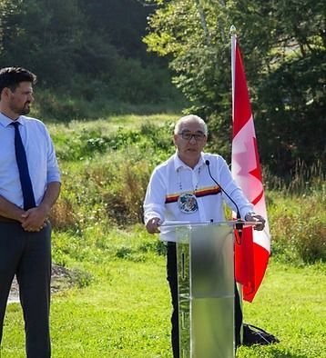 A man is standing at a podium in front of a canadian flag.