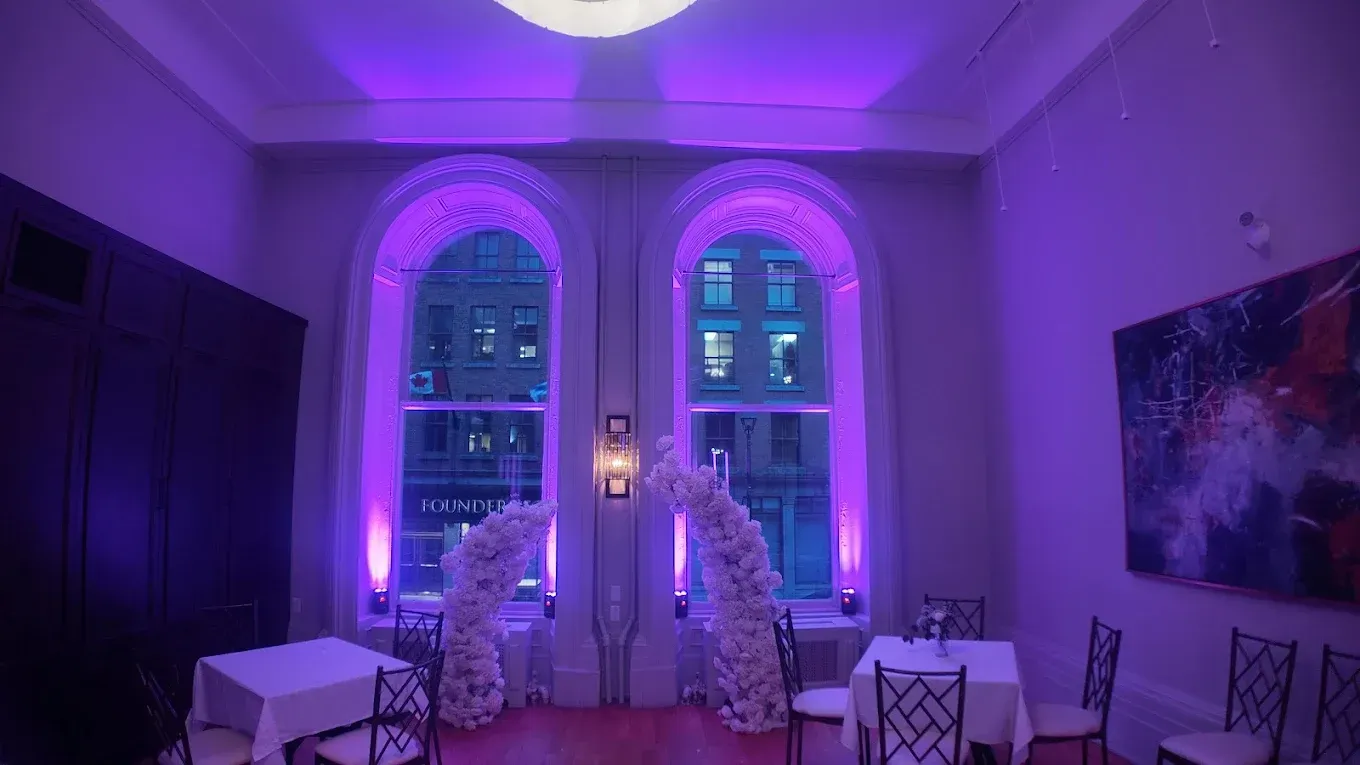 A room with tables and chairs and purple lights on the ceiling.