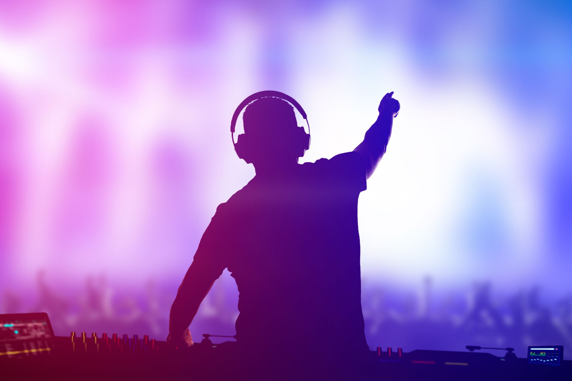 A silhouette of a dj wearing headphones playing music at a party.