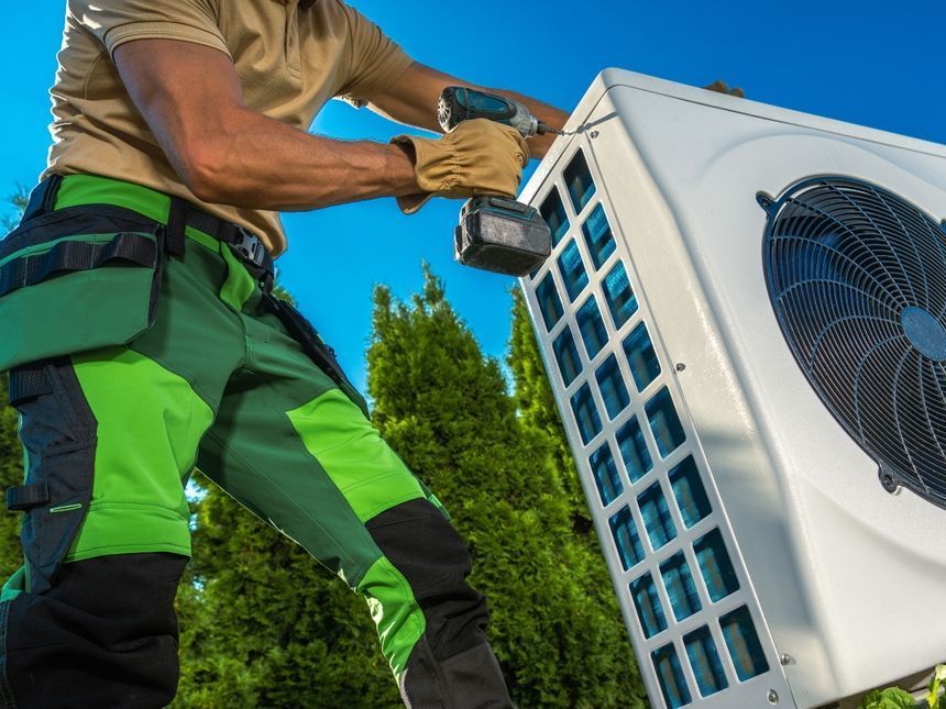 Un homme travaille sur un climatiseur avec une perceuse.