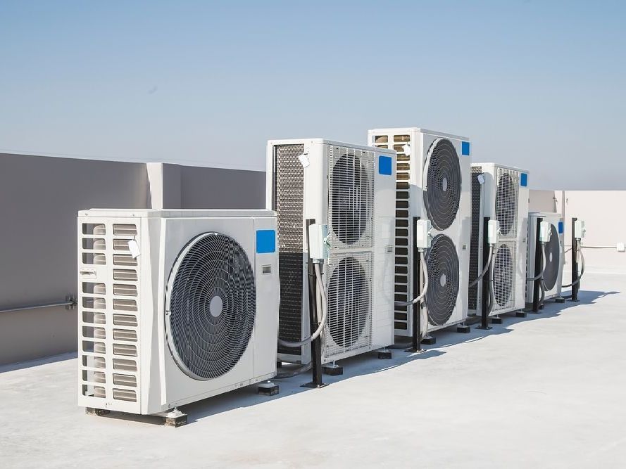 Une rangée de climatiseurs est alignée sur un toit.