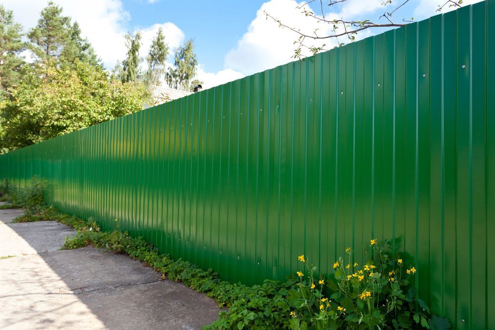 A Green Metal Fence is Surrounded by Grass and Trees — We Do Fencing in Sunshine Acres, QLD