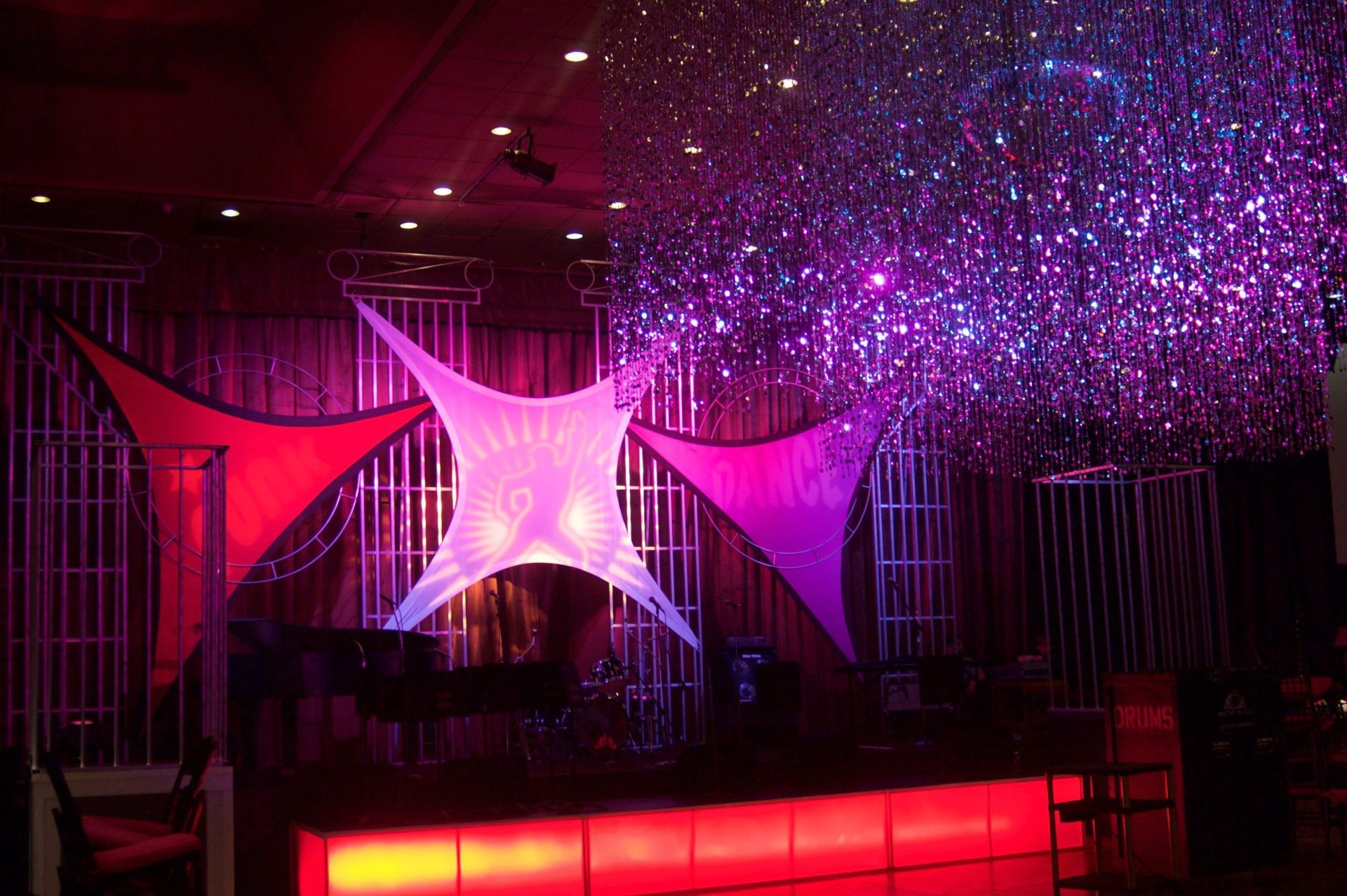 A dj is playing music in a room with purple and red lights