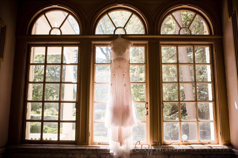 A wedding dress is hanging in a window.
