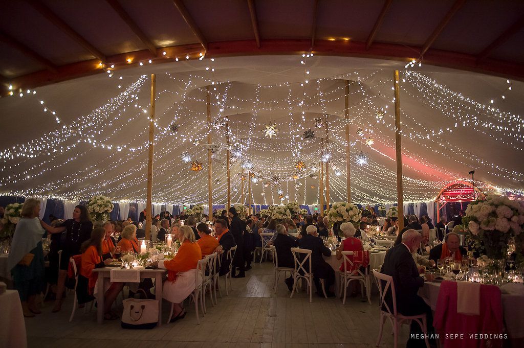 A large group of people are sitting at tables under a tent.