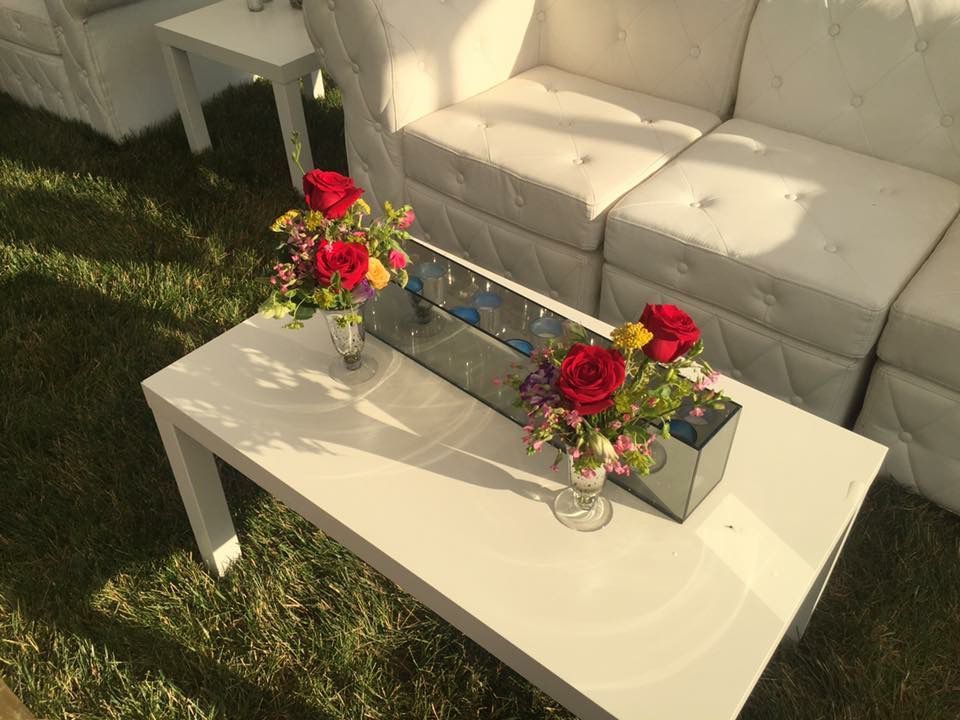 A white coffee table with two vases of flowers on it