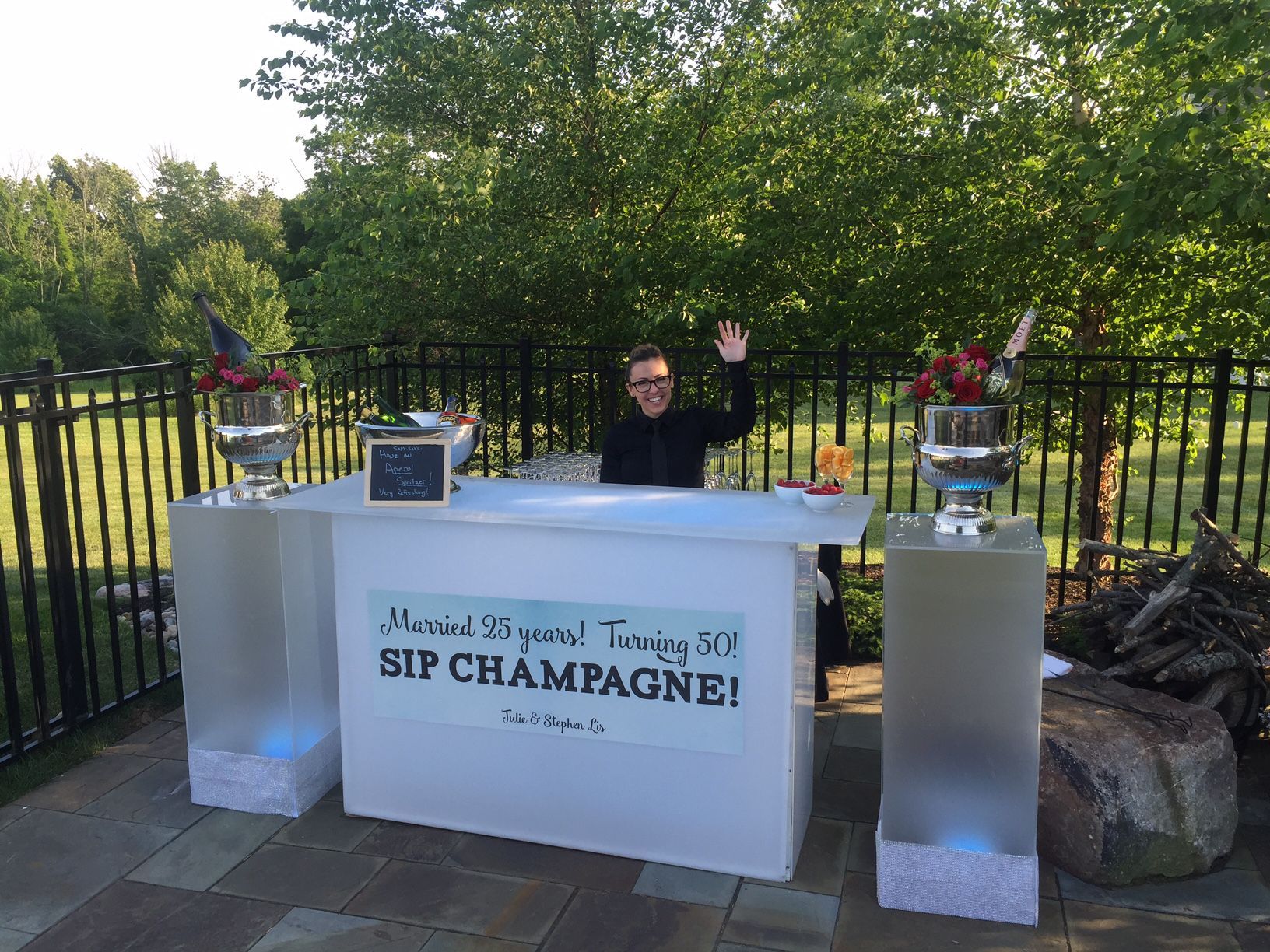 A man is standing in front of a bar that says sip champagne.