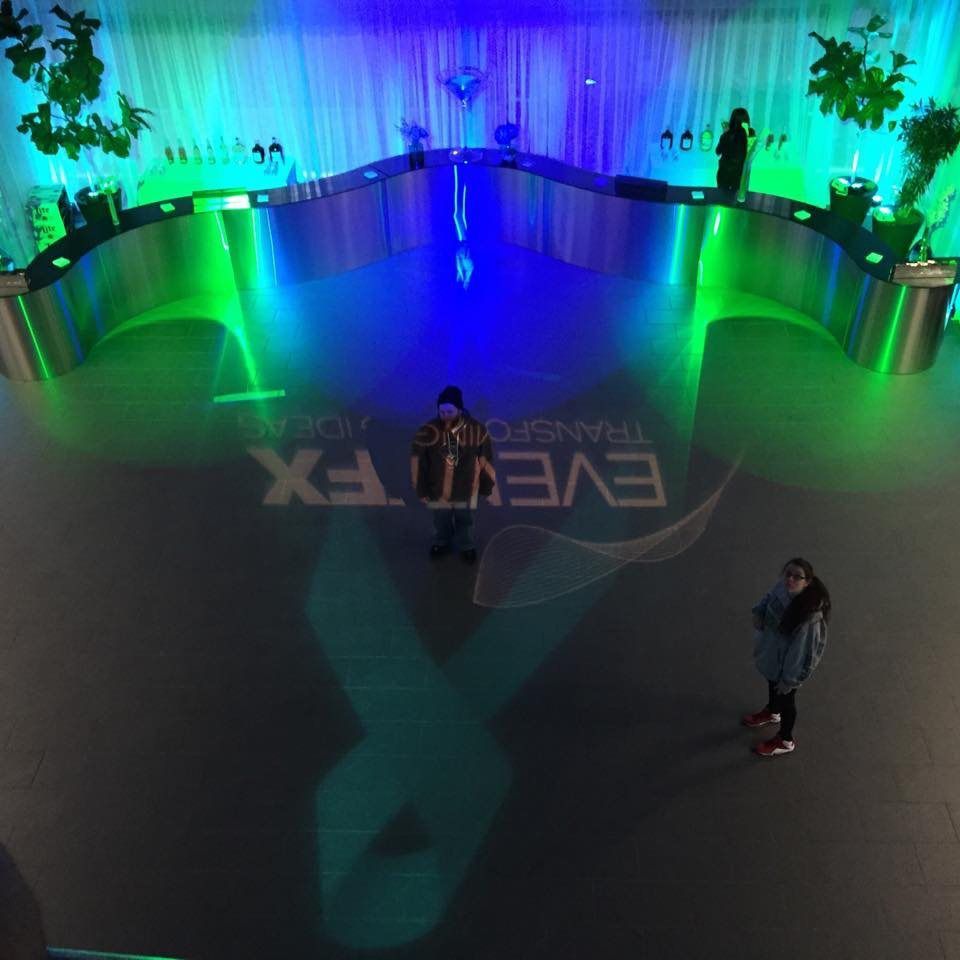 A woman stands in front of a large event fx sign