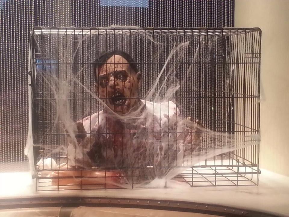 A man is wrapped in plastic while sitting in a cage.