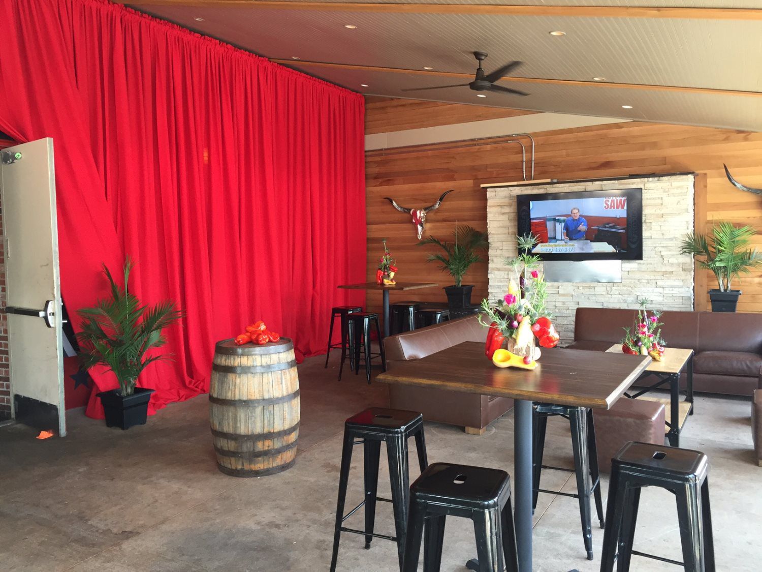 A living room with tables , stools , a barrel and a television.
