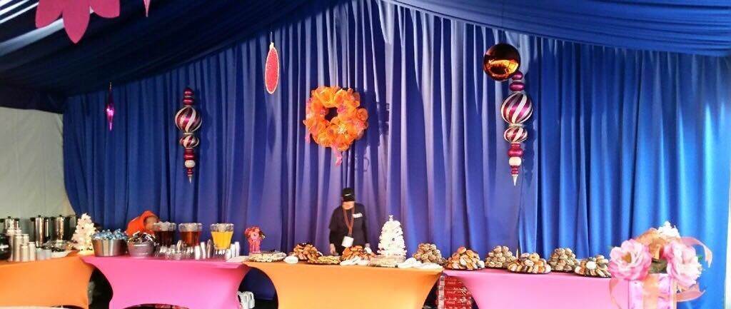 A man is standing in front of a stage with a blue curtain behind him.