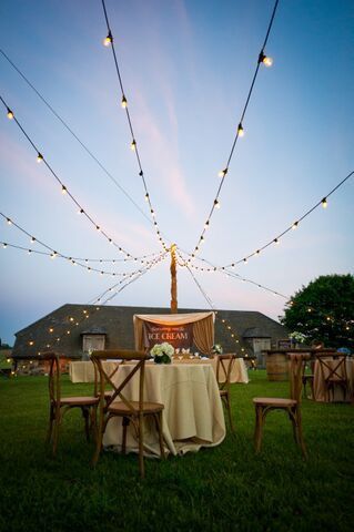 A table and chairs are sitting in the grass under string lights.