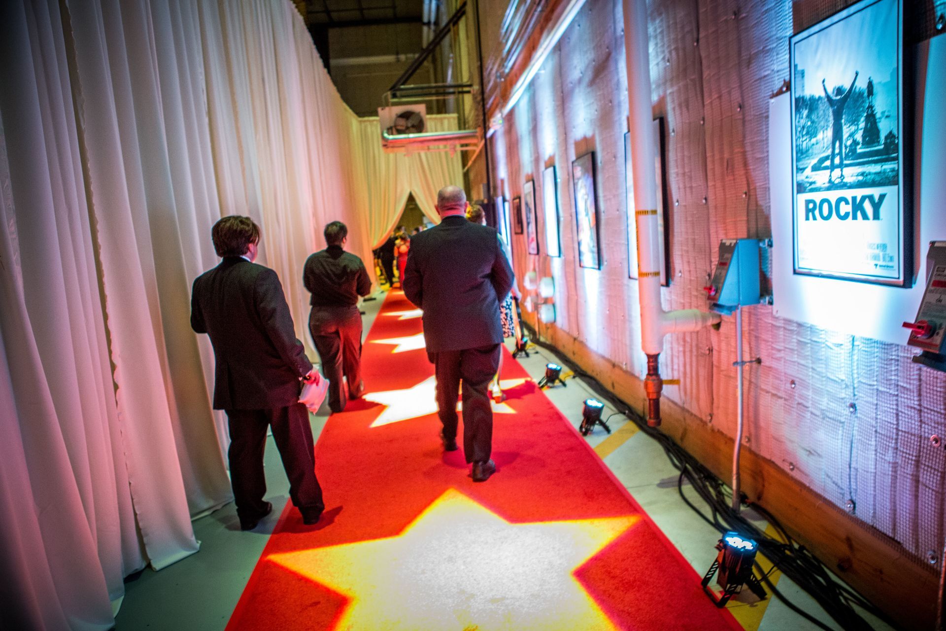 A group of people are walking down a red carpet with stars on it.