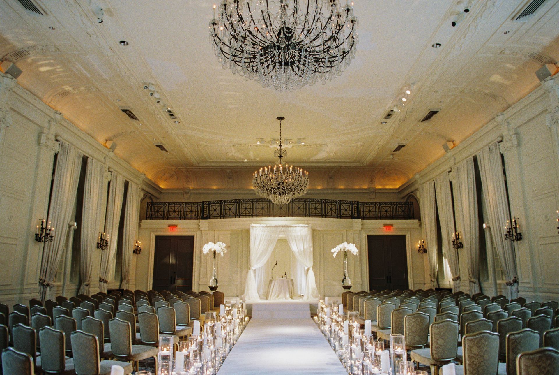 A wedding ceremony is taking place in a large room with a chandelier hanging from the ceiling.