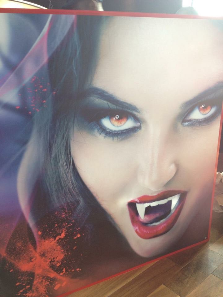 A close up of a woman 's face with vampire teeth