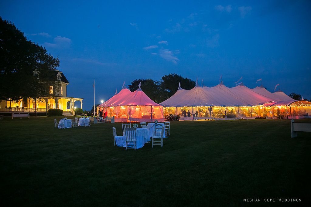 A group of tents are lit up at night in a field