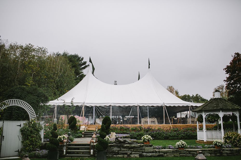A large white tent is sitting in the middle of a lush green field.