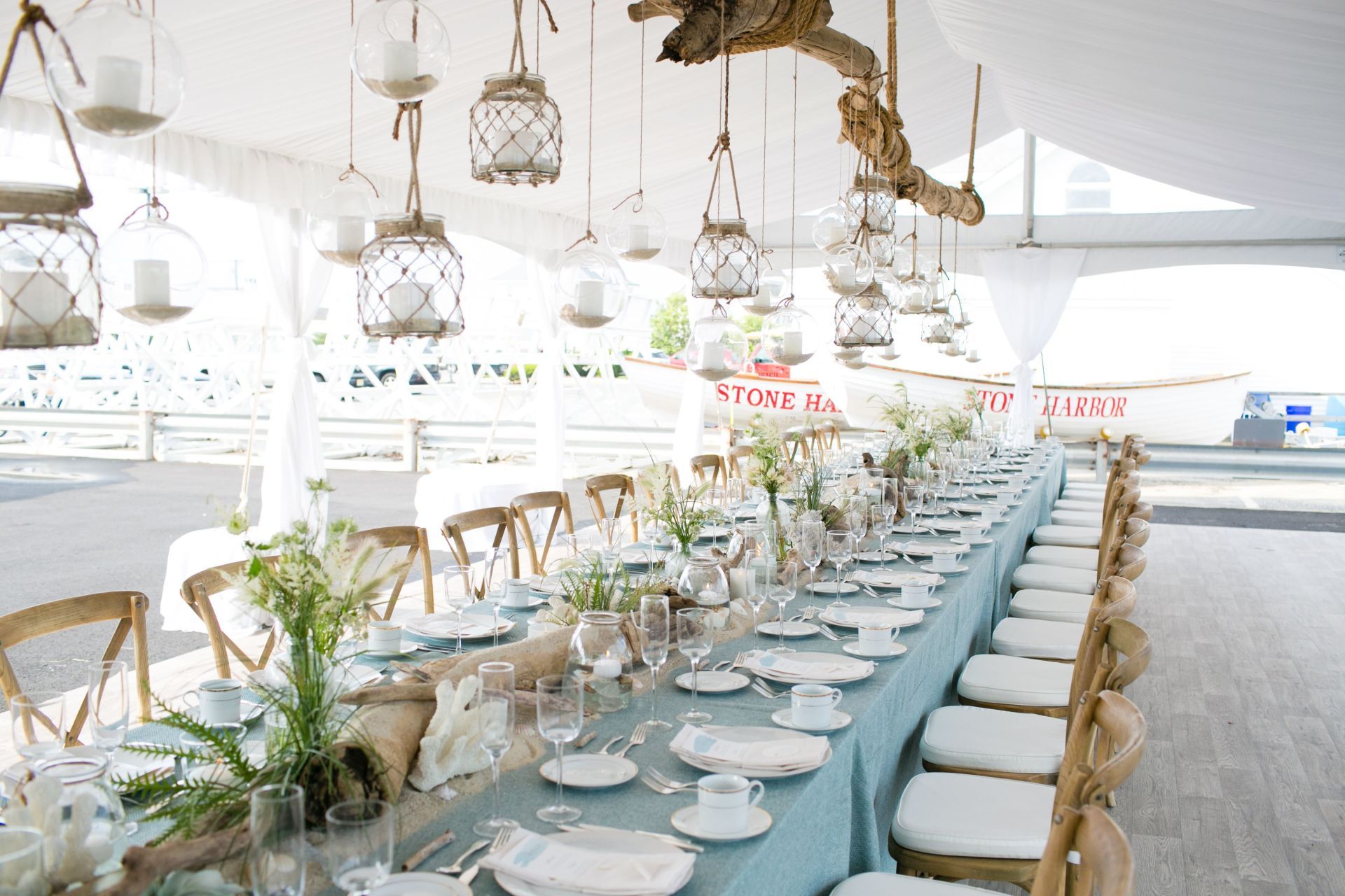 A long table is set for a wedding reception with lanterns hanging from the ceiling