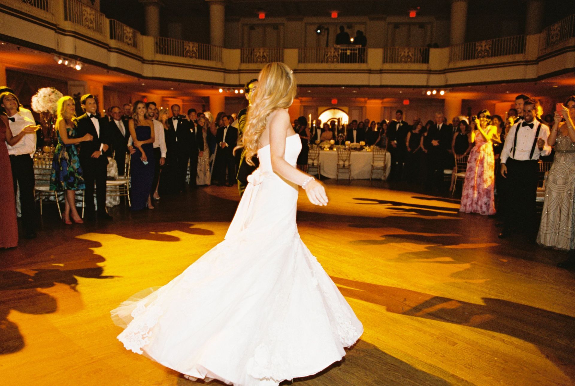 A woman in a wedding dress is dancing in front of a crowd