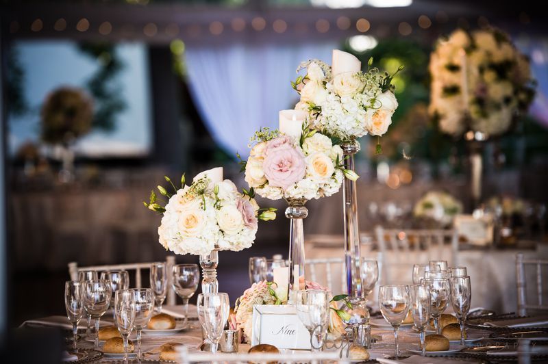 A table set for a wedding reception with flowers and glasses on it.